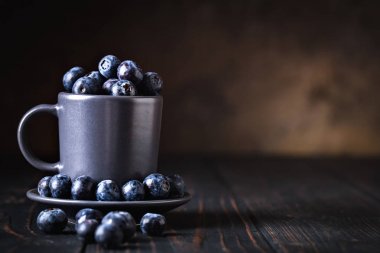 Ahududu ve yaban mersini karanlık bir arka plan üzerinde bir Fincan içinde. Yaz ve sağlıklı gıda konsepti. Kopyalama alanı ile arka plan. Seçici odak. Yatay.