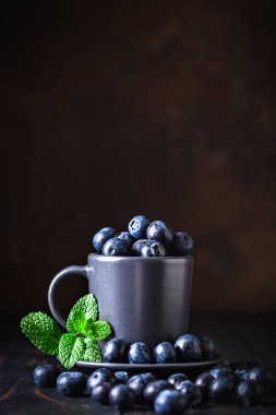 Ahududu ve yaban mersini karanlık bir arka plan üzerinde bir Fincan içinde. Yaz ve sağlıklı gıda konsepti. Kopyalama alanı ile arka plan. Seçici odak. Dikey.