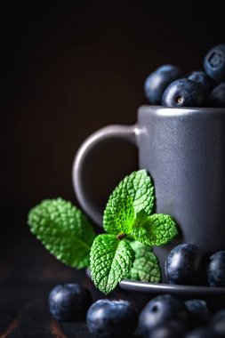 Ahududu ve yaban mersini karanlık bir arka plan üzerinde bir Fincan içinde. Yaz ve sağlıklı gıda konsepti. Kopyalama alanı ile arka plan. Seçici odak. Dikey.