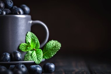 Ahududu ve yaban mersini karanlık bir arka plan üzerinde bir Fincan içinde. Yaz ve sağlıklı gıda konsepti. Kopyalama alanı ile arka plan. Seçici odak. Yatay.