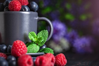 Ahududu ve yaban mersini karanlık bir arka plan üzerinde bir Fincan içinde. Yaz ve sağlıklı gıda konsepti. Kopyalama alanı ile arka plan. Seçici odak. Yatay.