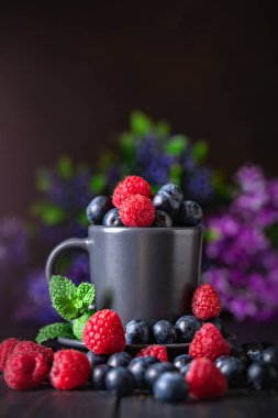 Ahududu ve yaban mersini karanlık bir arka plan üzerinde bir Fincan içinde. Yaz ve sağlıklı gıda konsepti. Kopyalama alanı ile arka plan. Seçici odak. Dikey.