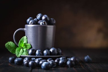 Ahududu ve yaban mersini karanlık bir arka plan üzerinde bir Fincan içinde. Yaz ve sağlıklı gıda konsepti. Kopyalama alanı ile arka plan. Seçici odak. Yatay.