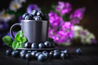 Karanlık bir arka plan üzerinde bir Fincan yaban mersini. Yaz ve sağlıklı gıda konsepti. Kopyalama alanı ile arka plan. Seçici odak. Yatay.