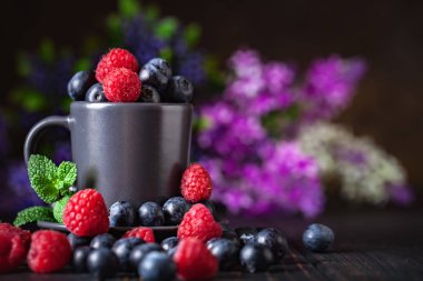 Ahududu ve yaban mersini karanlık bir arka plan üzerinde bir Fincan içinde. Yaz ve sağlıklı gıda konsepti. Kopyalama alanı ile arka plan. Seçici odak. Yatay.