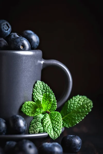 Karanlık bir arka plan üzerinde bir Fincan yaban mersini. Yaz ve sağlıklı gıda konsepti. Kopyalama alanı ile arka plan. Seçici odak. Dikey.