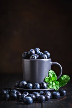 Karanlık bir arka plan üzerinde bir Fincan yaban mersini. Yaz ve sağlıklı gıda konsepti. Kopyalama alanı ile arka plan. Seçici odak. Dikey.