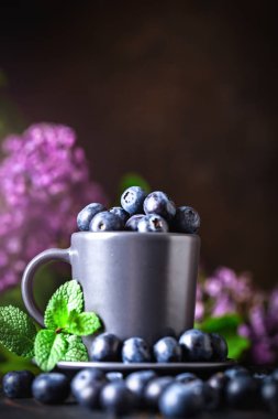 Karanlık bir arka plan üzerinde bir Fincan yaban mersini. Yaz ve sağlıklı gıda konsepti. Kopyalama alanı ile arka plan. Seçici odak. Dikey.