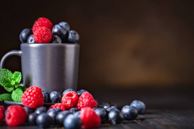 Ahududu ve yaban mersini karanlık bir arka plan üzerinde bir Fincan içinde. Yaz ve sağlıklı gıda konsepti. Kopyalama alanı ile arka plan. Seçici odak. Yatay.