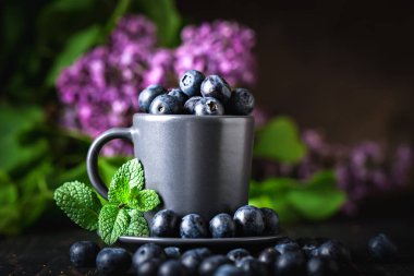 Karanlık bir arka plan üzerinde bir Fincan yaban mersini. Yaz ve sağlıklı gıda konsepti. Kopyalama alanı ile arka plan. Seçici odak. Yatay.