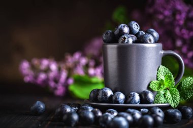 Karanlık bir arka plan üzerinde bir Fincan yaban mersini. Yaz ve sağlıklı gıda konsepti. Kopyalama alanı ile arka plan. Seçici odak. Yatay.