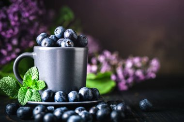 Karanlık bir arka plan üzerinde bir Fincan yaban mersini. Yaz ve sağlıklı gıda konsepti. Kopyalama alanı ile arka plan. Seçici odak. Yatay.