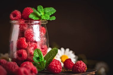 Fincanda ahududu ve koyu bir arka plan. Yaz ve sağlıklı gıda konsepti. Kopya alanı olan bir arkaplan. Seçici odaklanma. Dikey.