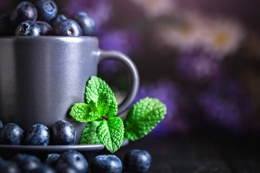 Karanlık bir arka plan üzerinde bir Fincan yaban mersini. Yaz ve sağlıklı gıda konsepti. Kopyalama alanı ile arka plan. Seçici odak. Yatay.