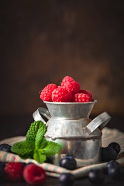 Ahududu ve yaban mersini karanlık bir arka plan üzerinde bir Fincan içinde. Yaz ve sağlıklı gıda konsepti. Kopyalama alanı ile arka plan. Seçici odak. Dikey.