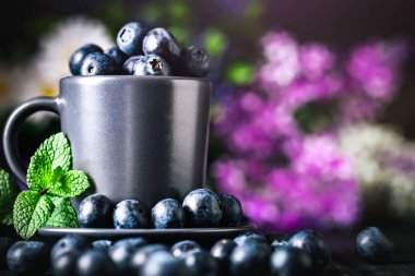 Karanlık bir arka plan üzerinde bir Fincan yaban mersini. Yaz ve sağlıklı gıda konsepti. Kopyalama alanı ile arka plan. Seçici odak. Yatay.