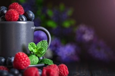 Ahududu ve yaban mersini karanlık bir arka plan üzerinde bir Fincan içinde. Yaz ve sağlıklı gıda konsepti. Kopyalama alanı ile arka plan. Seçici odak. Yatay.