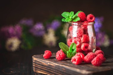 Fincanda ahududu ve koyu bir arka plan. Yaz ve sağlıklı gıda konsepti. Kopya alanı olan bir arkaplan. Seçici odaklanma. Dikey.