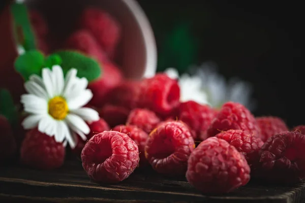 Málna egy piros csésze Kamilla és a levelek egy sötét háttér. Nyári és egészséges élelmiszer-koncepció. Háttér másolási területtel. Szelektív fókusz. — Stock Fotó