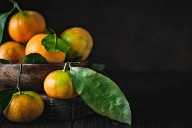 Eski moda bir masa üzerinde yaprakları olan mandalinalar. Seçici odaklanma. Yatay.