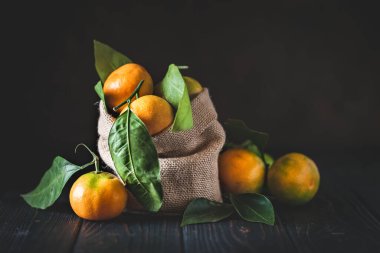 Eski moda bir masa üzerinde yaprakları olan mandalinalar. Seçici odaklanma. Yatay.