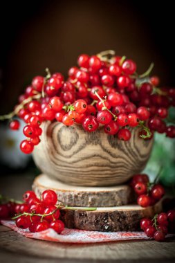 Koyu kırsal ahşap masada taze kırmızı frenk üzümü tabağı. Kopya alanı olan bir arkaplan. Seçici odak.