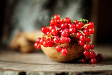 Koyu kırsal ahşap bir masada fincanda taze kırmızı frenk üzümü. Kopyalamak için alanı olan bir arka plan. Seçici odak.