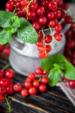 Koyu kırsal ahşap bir masada fincanda taze kırmızı frenk üzümü. Kopyalamak için alanı olan bir arka plan. Seçici odak.