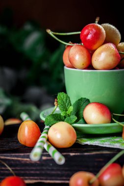 Koyu, ahşap bir masada kupada taze kiraz. Kopyalamak için alanı olan bir arka plan. Seçici odak.