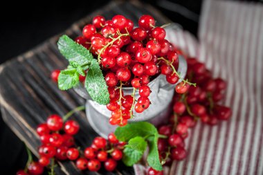 Koyu kırsal ahşap bir masada fincanda taze kırmızı frenk üzümü. Kopyalamak için alanı olan bir arka plan. Seçici odak.