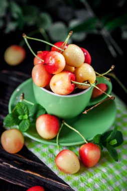 Koyu, ahşap bir masada kupada taze kiraz. Kopyalamak için alanı olan bir arka plan. Seçici odak.
