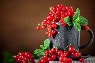 Koyu kırsal ahşap bir masada fincanda taze kırmızı frenk üzümü. Kopyalamak için alanı olan bir arka plan. Seçici odak.