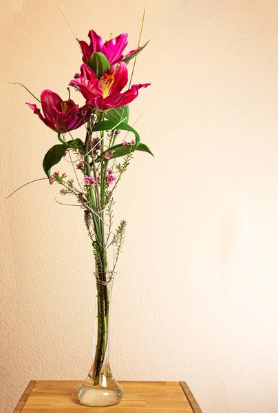 Bouguet con flores de lirio rojo en un jarrón — Foto de Stock