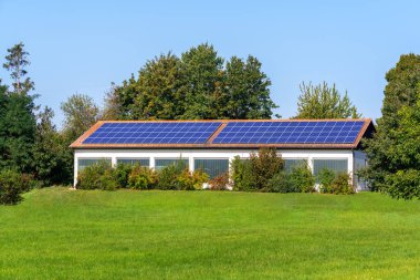 Bir tarım binasının çatısında güneş enerjisi toplayıcıları olan yeşil enerji.
