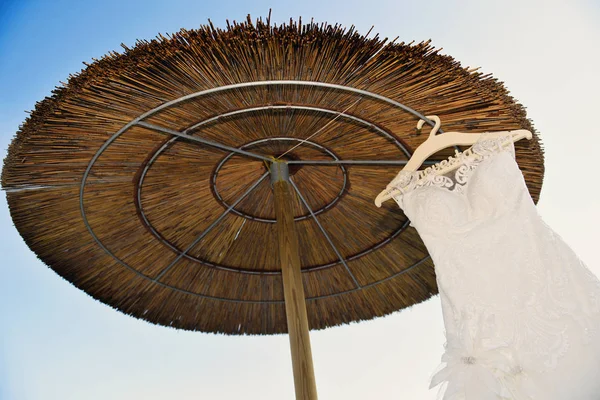 沙滩上挂着稻草伞的白色连衣裙 — 图库照片