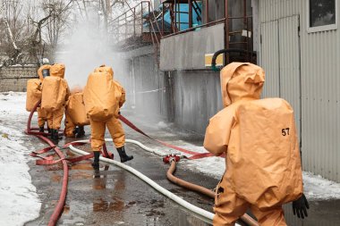 Kurtarma ekipleri kapsül takım elbiseli bir su engel toksik Ajan bulutu yolda koymak.