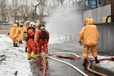 Kurtarma ekipleri kapsül takım elbiseli bir su engel toksik Ajan bulutu yolda koymak.