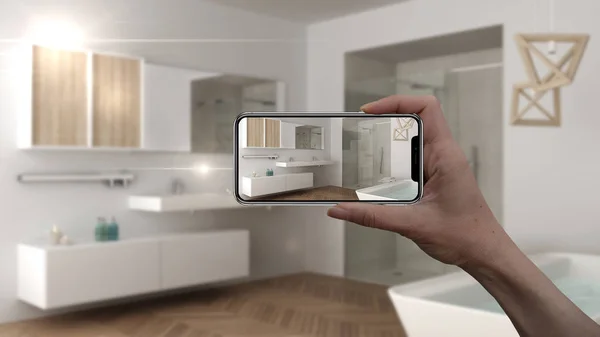 Hand holding smart phone, AR application, simulate furniture and interior design products in real home, architect designer concept, blur background, scandinavian bathroom