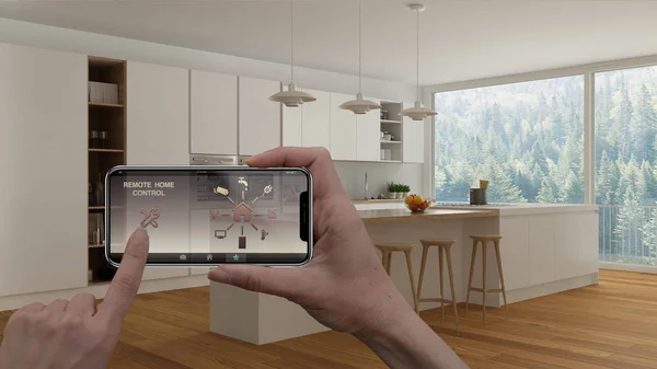 Remote home control system on a digital smart phone tablet. Device with app icons. Interior of minimalist white kitchen in the background, architecture design.
