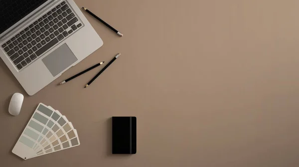 Stylish minimal office table desk. Workspace with laptop, notebook, pencils and sample color palette on beige background. Flat lay, top view