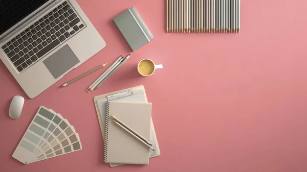 Stylish minimal office table desk. Workspace with laptop, notebook, pencils, coffee cup and sample color palette on pastel pink background. Flat lay, top view