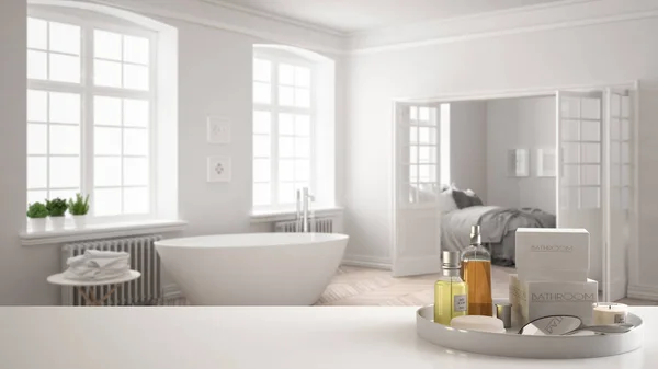 Spa, hotel bathroom concept. White table top or shelf with bathing accessories, toiletries, over blurred vintage bathroom with bedroom, modern architecture interior design