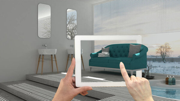 Augmented reality concept. Hand holding tablet with AR application used to simulate furniture and interior design products in real home, modern bathroom with sofa