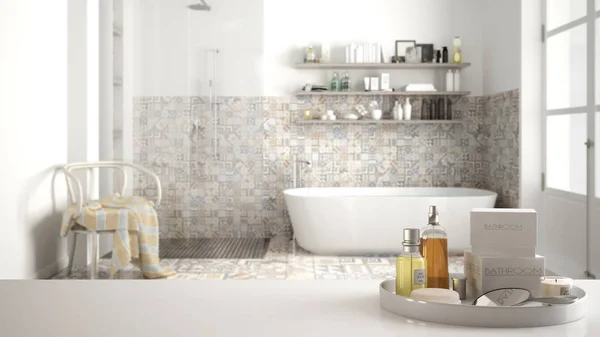 Spa, hotel bathroom concept. White table top or shelf with bathing accessories, toiletries, over blurred vintage classic bathroom, modern architecture interior design