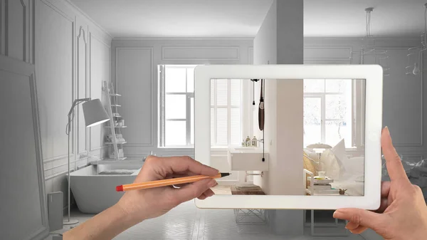 Hands holding and drawing on tablet showing bedroom and bathroom interior sketch. Total white minimalist interior in the background, architecture design presentation