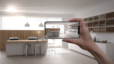 El holding akıllı telefon, Ar uygulama, mobilya ve iç tasarım ürünleri içinde gerçek ev, mimar tasarımcı kavramı simülasyonu, arka plan, ada ve dışkı ile minimalist mutfak bulanıklık