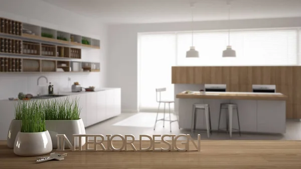 Wooden table, desk or shelf with potted grass plant, house keys and 3D letters making the words interior design, over blurred modern kitchen, project concept copy space background