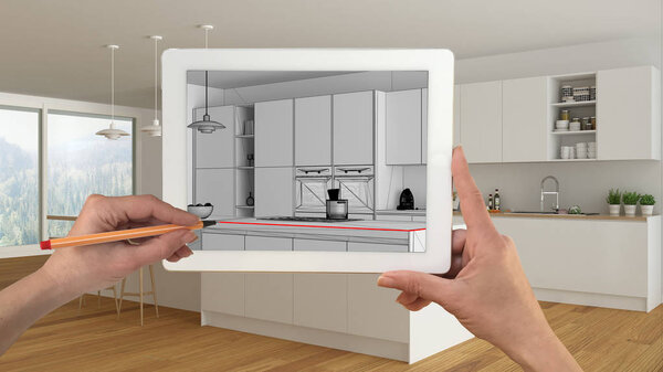 Руки держат и рисуют на планшете, показывая минималистичный белый и деревянный CAD эскиз кухни. Реальная отделка интерьера на заднем плане, презентация архитектурного дизайна
