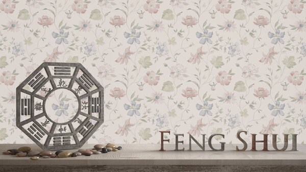 Wooden vintage table shelf with ba gua and 3d letters making the word feng shui with abstract floral background with copy space, zen concept interior design