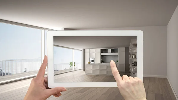 Augmented reality concept. Hand holding tablet met Ar toepassing gebruikt om te simuleren van meubelen en design producten in leeg interieur met parketvloer, klassieke witte keuken — Stockfoto